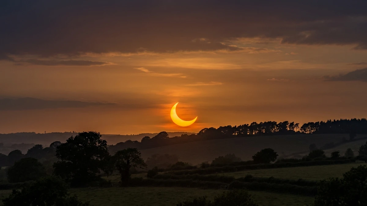 A thin orange crescent sun low over a western horizon during the deep partial solar eclipse of 12 August 2026