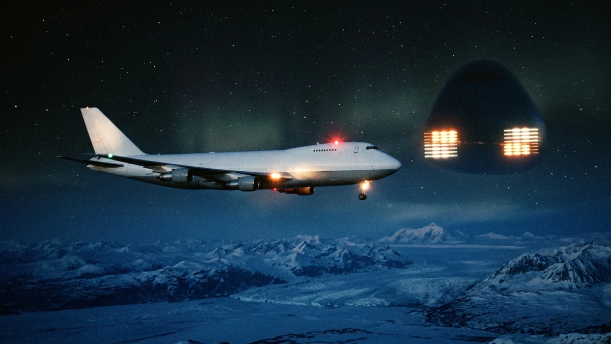 A Boeing 747 freighter at night over the snowy Alaskan interior with two rectangular grids of amber lights on a dark rounded shape holding position off its side