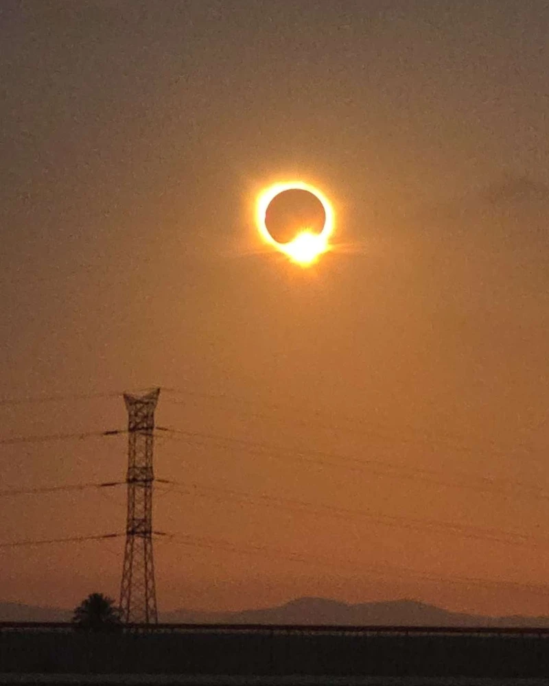 The diamond ring effect of the total solar eclipse of 12 August 2026, low in an orange sky above an electricity pylon near Valencia, Spain