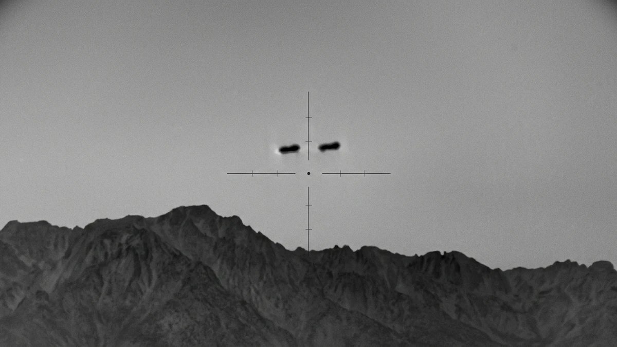 Thermal imager view showing two dark slow-moving objects above a mountain line
