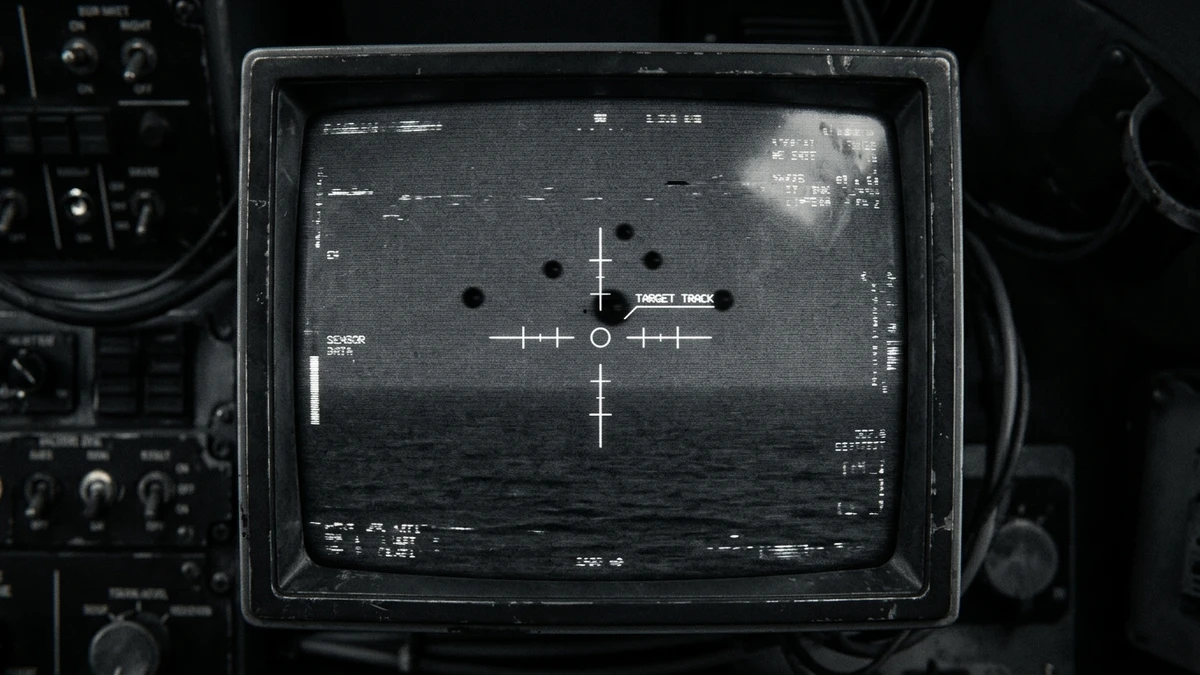 A grainy infrared sensor screen showing several small dark orbs over the sea, viewed from inside a military aircraft