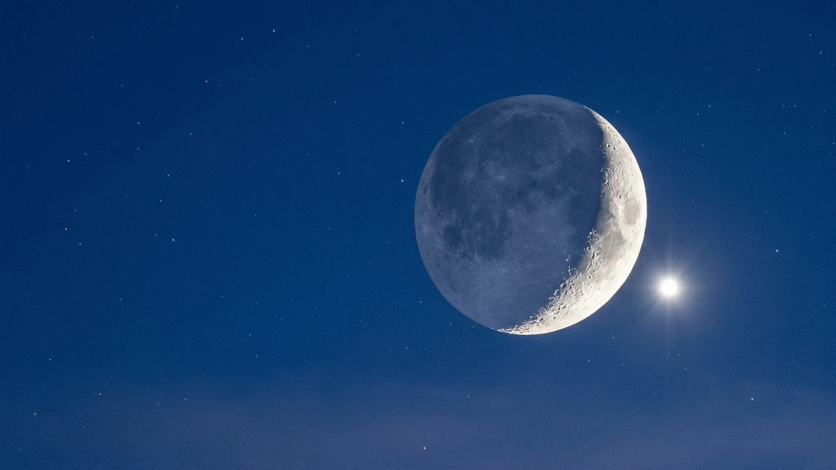 Close view of the thin crescent Moon with earthshine beside brilliant Venus in deep twilight