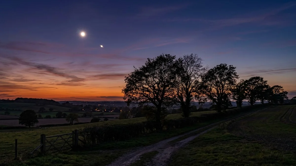 Venus and Jupiter shining in the western twilight sky above a countryside horizon
