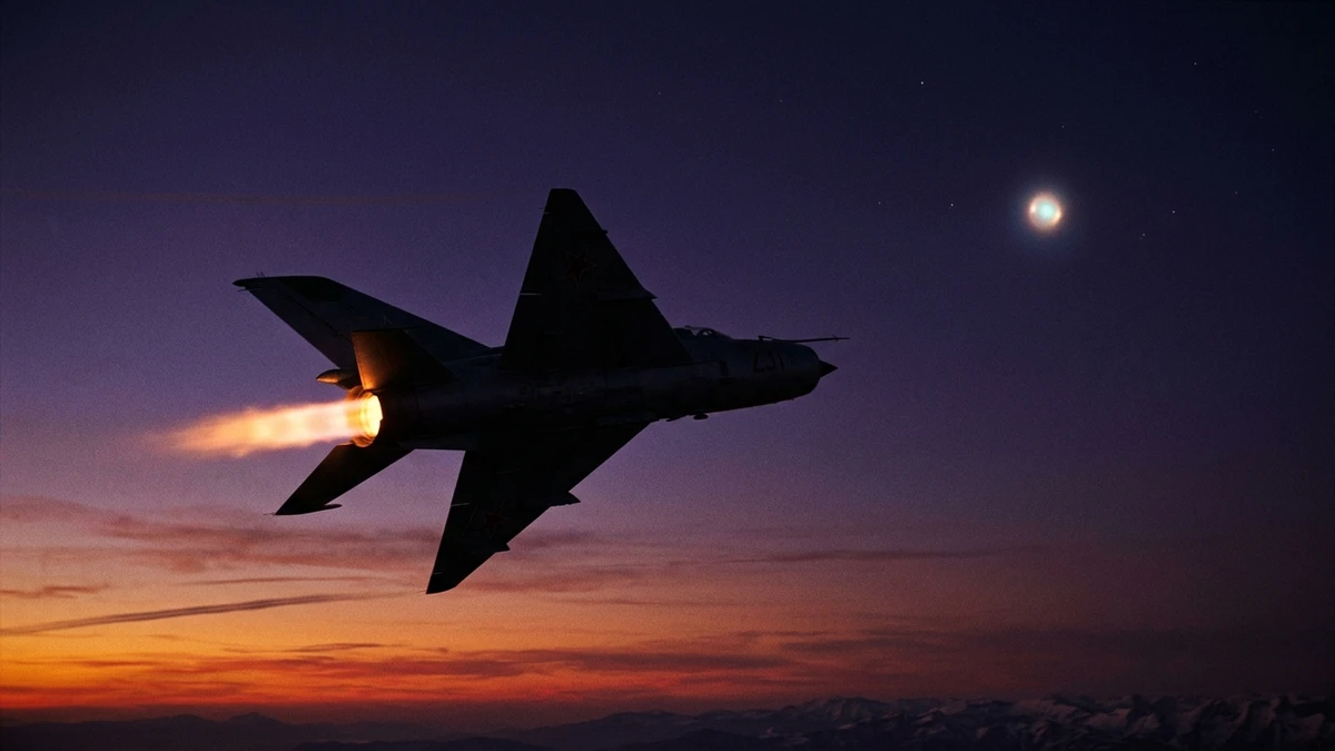 A silhouetted MiG fighter jet banking steeply against a twilight sky, afterburner glowing orange, with a faint luminous object ahead of it