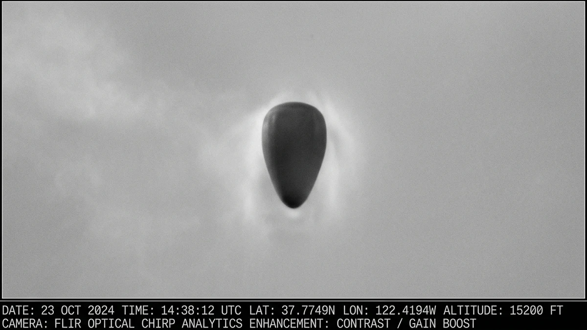 Enhanced surveillance photograph showing a dark, teardrop-shaped solid object against pale sky — the type of Sandia National Laboratories image analysis used on the Pantex UAP photographs