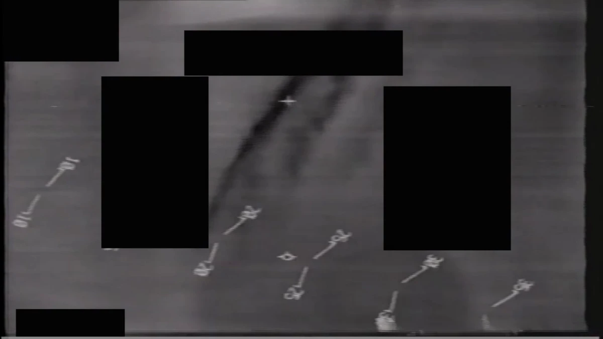 Grainy monochrome 1996 infrared frame from DOW-UAP-PR113 showing a faint diagonal streak crossing the upper part of the frame between black redaction boxes, with tick-marked scale lines visible