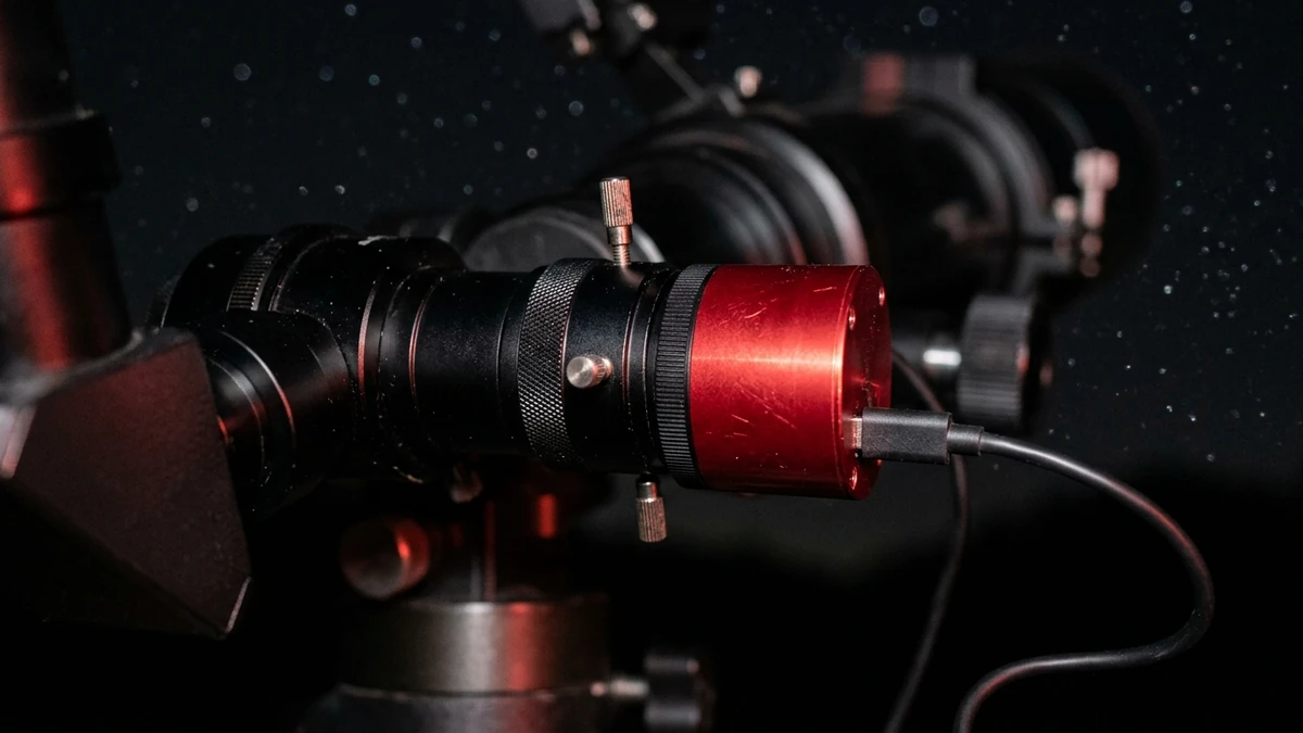 Close-up of a telescope focuser at night with a Barlow lens, an atmospheric dispersion corrector and a small planetary camera stacked together