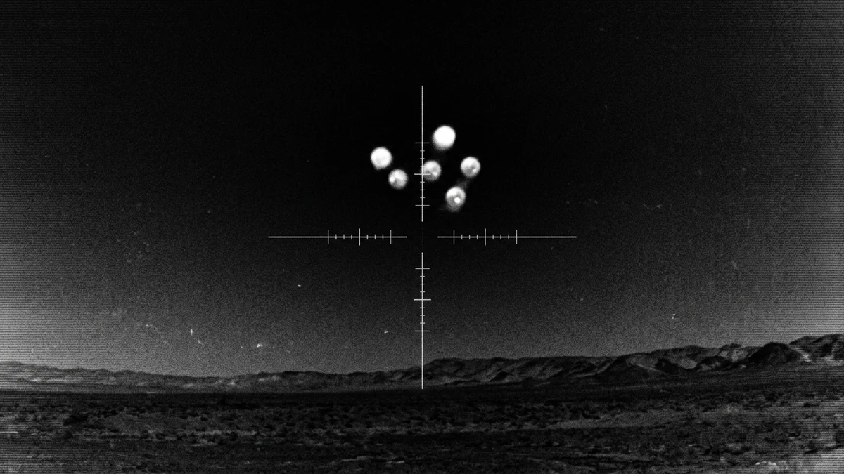 Infrared sensor view showing six small bright spherical objects grouped together against a dark sky