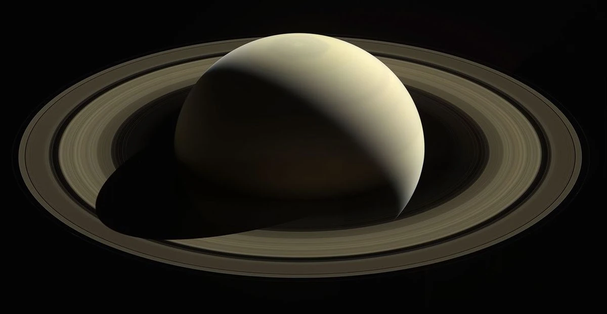 Saturn backlit by the Sun in Cassini's farewell image, with Earth visible as a pale blue dot just inside the outermost ring