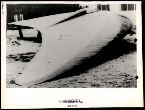 A black and white photograph of a large, delta-winged aircraft prototype resting on the ground, marked as confidential.