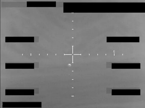 Redacted sensor image with a crosshair targeting an object.