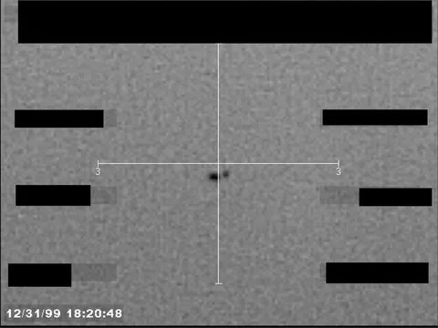 Redacted sensor image with a crosshair targeting a visible object.