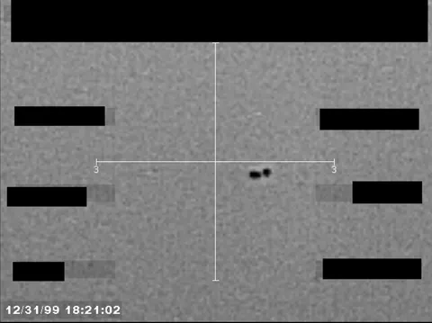 Redacted sensor image with a crosshair targeting a visible object.