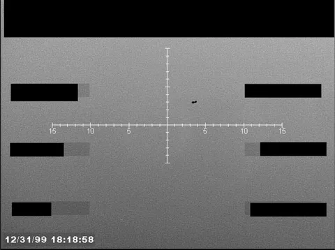 Redacted sensor image with a targeting reticle centered on an object.