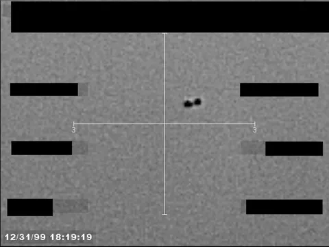 Redacted sensor image with a targeting reticle centered on an object.