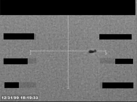 Redacted sensor image with a targeting reticle centered on an object.