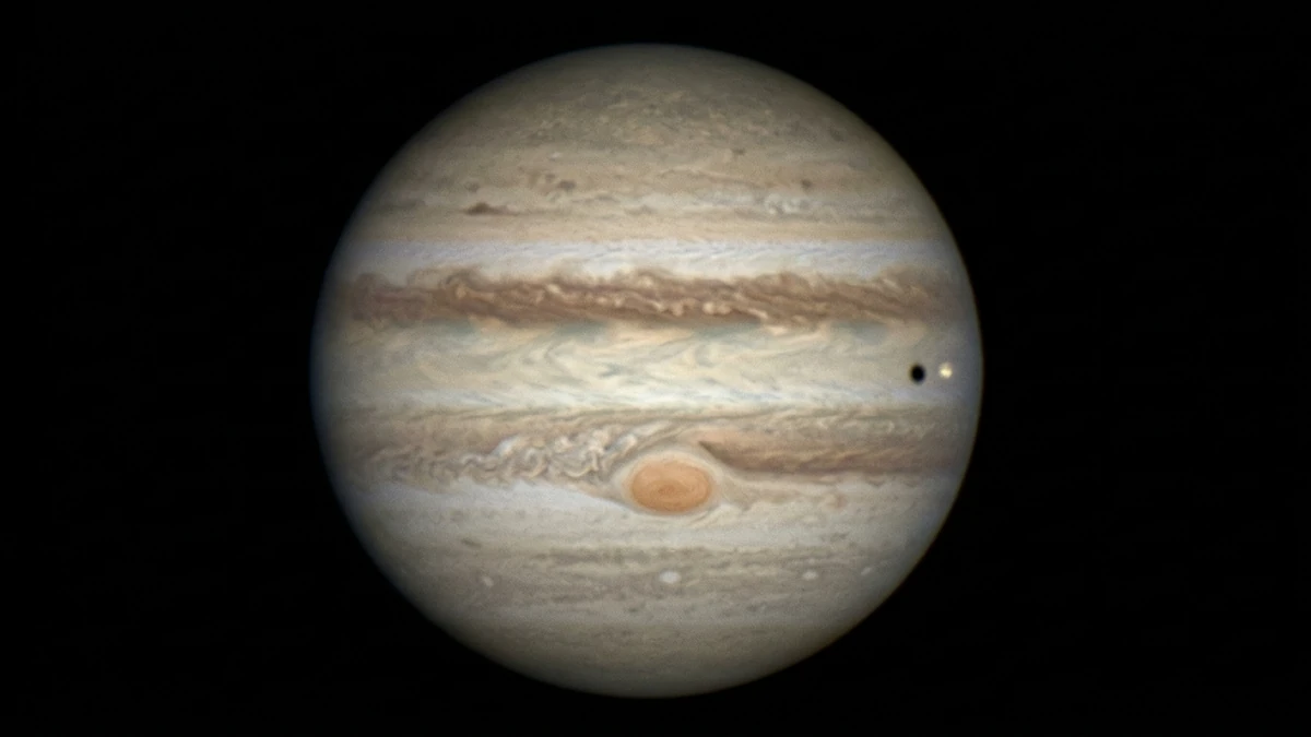 A stacked amateur image of Jupiter showing two dark equatorial belts, the Great Red Spot and a moon shadow