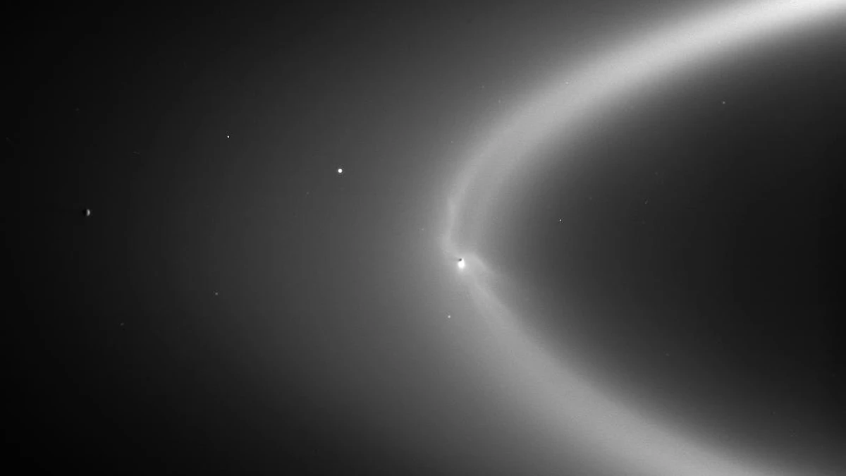 Wispy fingers of ice reaching from the moon Enceladus into Saturn's faint E ring, photographed by Cassini with the Sun behind