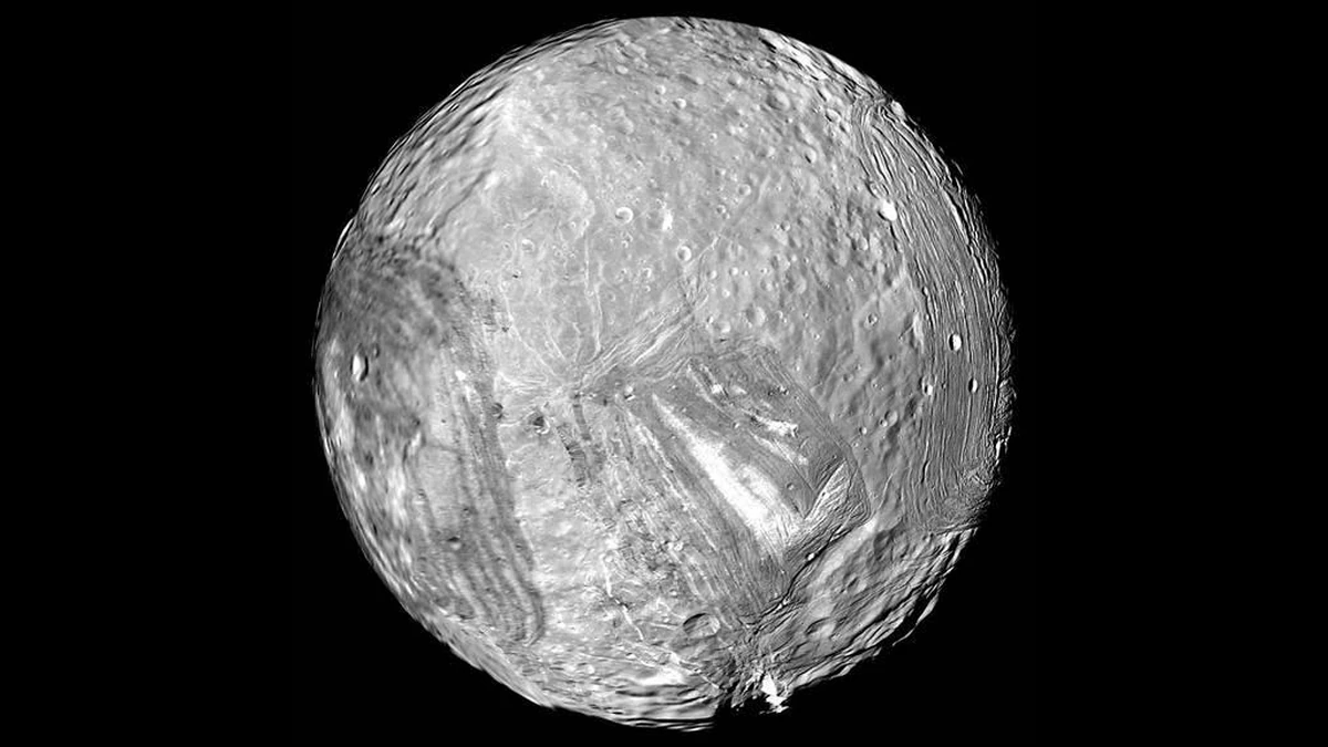 Black-and-white Voyager 2 image of Miranda's full disc, showing bright, grooved terrain on the lower half and craters on the upper half