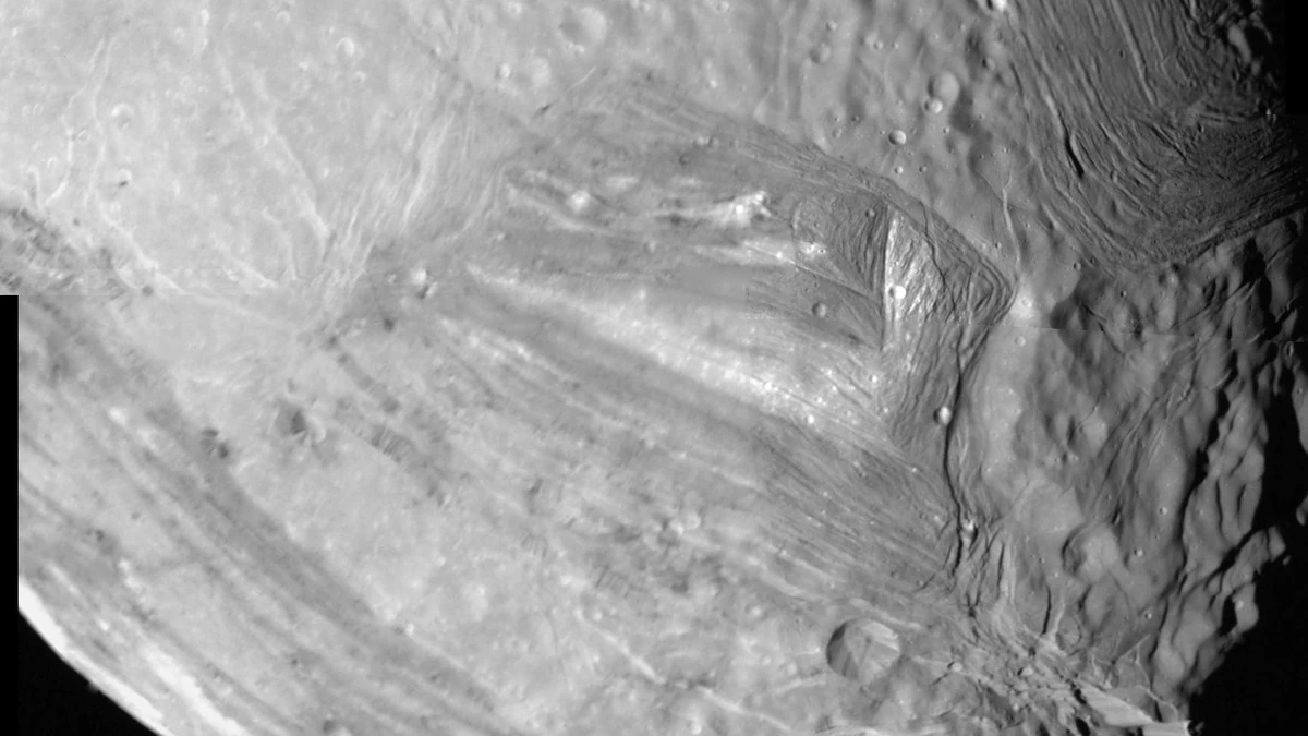 Black-and-white Voyager 2 mosaic of Miranda showing ridged and grooved terrain cut off sharply against smoother, cratered ground