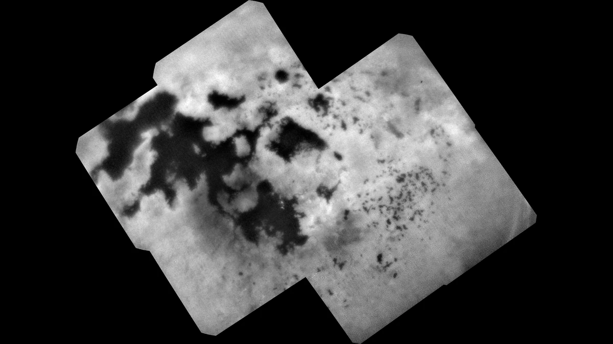 A black and white mosaic of Titan's north polar region, with large dark seas and many small dark lakes standing out against paler ground
