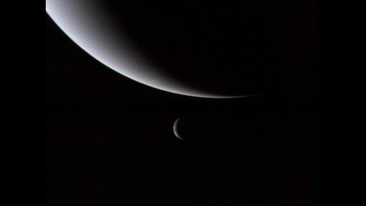 Voyager 2 view of Neptune as a large pale crescent at the top, with Triton as a small crescent below it against black space
